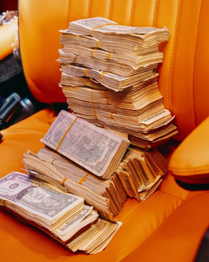 Close-up of bundled currency notes on a vibrant orange leather seat, symbolizing wealth.